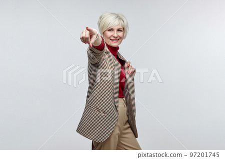 beautiful elderly woman with a smile points her finger at the camera. the concept of a business woman leader beautiful elderly woman with a smile points her finger at the camera. the concept of a business woman leader 97201745
