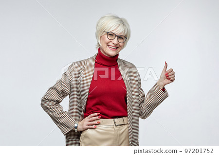 beautiful elderly woman with glasses gives a thumbs up. the concept of a business woman leader beautiful elderly woman with glasses gives a thumbs up. the concept of a business woman leader 97201752