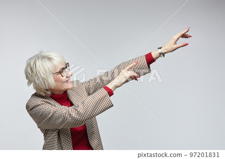 beautiful elderly woman with glasses points with her index finger at an empty seat. advertising concept of a business woman leader beautiful elderly woman with glasses points with her index finger at an empty seat. advertising concept of a business woman leader 97201831