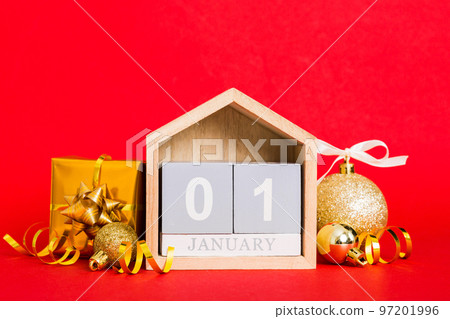 1 january. Christmas composition on colored background with a wooden calendar, with a gift box, toys, bauble copy space 1 january. Christmas composition on colored background with a wooden calendar, with a gift box, toys, bauble copy space 97201996