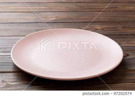 Perspective view of empty pink plate on wooden background. Empty space for your design Perspective view of empty pink plate on wooden background. Empty space for your design 97202074