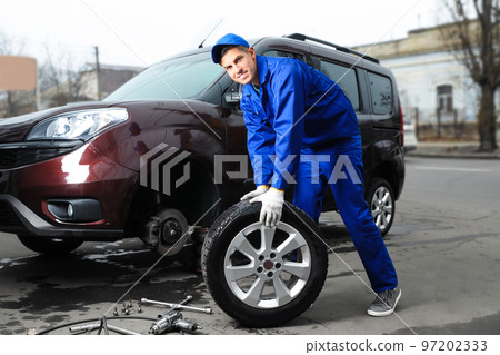 Worker changing car wheel at tire service Worker changing car wheel at tire service 97202333