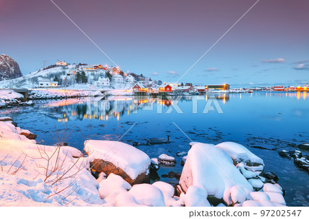 Dramatic evening cityscape of Reine town. Red rorbuers on the shoore of Reinefjorden. 97202547