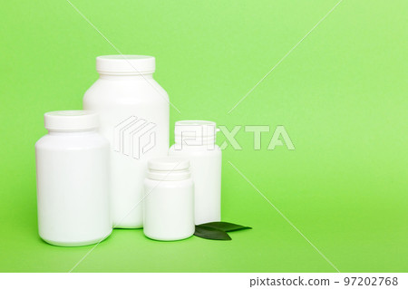 supplement pills with medicine bottle health care and medical top view. Vitamin tablets. Top view mockup bottle for pills and vitamins with green leaves, natural organic bio supplement, copy space 97202768