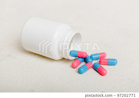 different drugs and health supplement pills poured from a medicine bottle health care and medical top view on colored background 97202771
