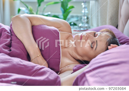 Mature woman with closed eyes sleeping in bed at home Mature woman with closed eyes sleeping in bed at home 97203084