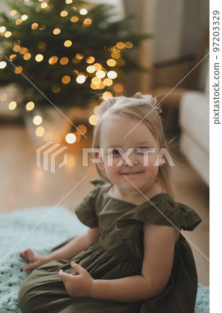 Cute little child girl and the Christmas tree indoors. Merry Christmas and Happy New Year concept Cute little child girl and the Christmas tree indoors. Merry Christmas and Happy New Year concept 97203329