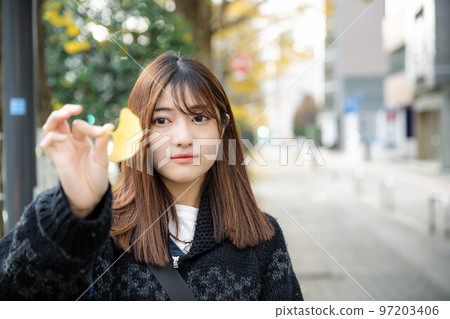 A woman holding a ginkgo tree in the city A woman holding a ginkgo tree in the city 97203406