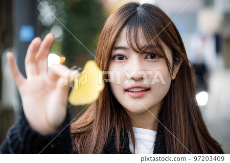 A woman holding a ginkgo tree in the city A woman holding a ginkgo tree in the city 97203409