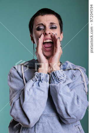 Upset frustrated female aggressively screeming in front of camera while being anger about the news. Stressed person having agressive expression during studio shot standing over isolated background Upset frustrated female aggressively screeming in front of camera while being anger about the news. Stressed person having agressive expression during studio shot standing over isolated background 97204594