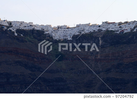 Row of white houses built on the cliffs of Santorini at dawn 97204792