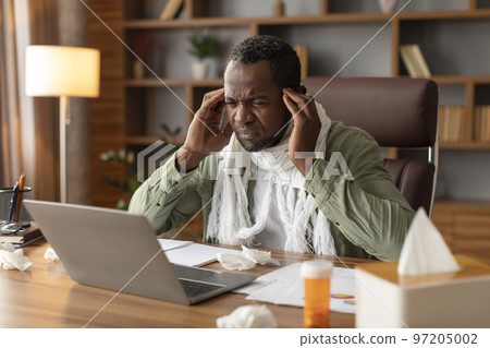 Despair mature black male with scarf suffers from headache, pain, fever, looks at computer, take head with hands Despair mature black male with scarf suffers from headache, pain, fever, looks at computer, take head with hands 97205002