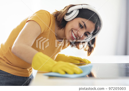 Cheerful Young Arab Woman Listening Music While Cleaning Kitchen Counter Cheerful Young Arab Woman Listening Music While Cleaning Kitchen Counter 97205003