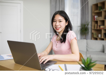 Portrait of happy asian woman using laptop computer, sitting at desk at home and smiling at camera, copy space Portrait of happy asian woman using laptop computer, sitting at desk at home and smiling at camera, copy space 97205032