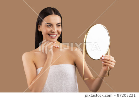 Happy beautiful millennial woman wrapped in towel looking at mirror 97205221
