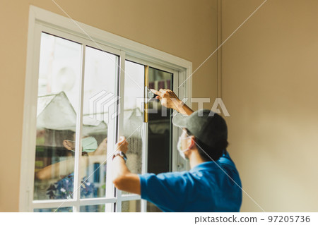Worker use scraper cleaning window before installing tinting window film 97205736