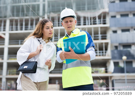 Man engineer and a young woman customer discuss a construction project 97205889