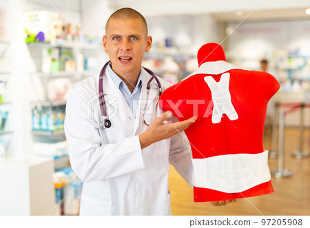 Positive pharmacist or doctor offers an orthopedic patch for the back. Demonstration of the work plaster on mannequin 97205908