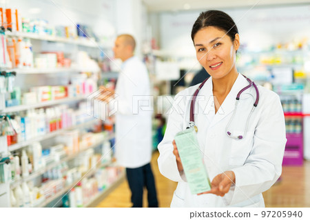 Oriental female pharmacist standing in salesroom of drugstore Oriental female pharmacist standing in salesroom of drugstore 97205940