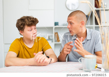 Portrait of teen boy having conversation with man in home Portrait of teen boy having conversation with man in home 97206015