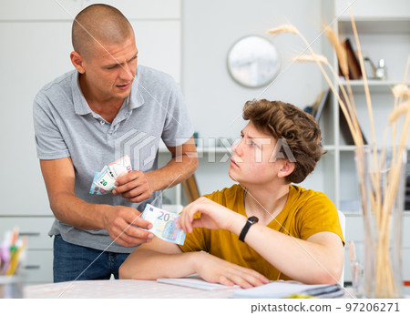 Father and son counting money while sitting at table at home 97206271