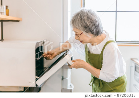 Elderly asian woman using microwave to cook food in home kitchen (smiling) 97206313