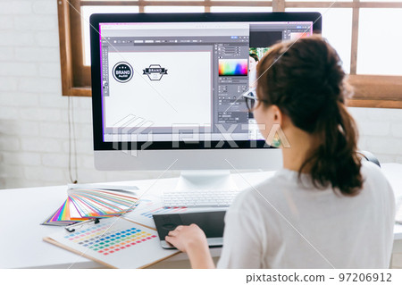A graphic designer and illustrator woman who works on logo design with a pen tablet 97206912