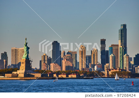 Statue of Liberty with skyscrapers surrounding from waters in golden light Statue of Liberty with skyscrapers surrounding from waters in golden light 97208424