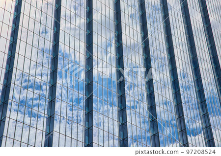 Detail of huge glass skyscraper reflecting blue sky and clouds 97208524