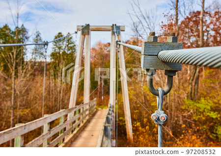 Detail of support ropes for large suspension bridge leading into fall forest 97208532