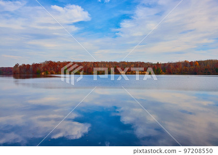 Crystal clear lake surface with fall forests lining the coast in Michigan 97208550