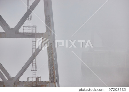 Support pillars of old steel bridge with ladders fading in extreme weather foggy morning 97208583