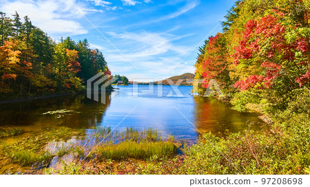 Low view of lake with blue skies and colorful fall hills 97208698