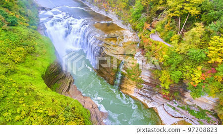 Aerial over stunning raging waterfalls eroding cliffs with lush greenery and overlook for tourists 97208823