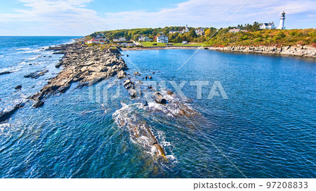 Rocky coastline from over water in Maine with lighthouse in background Rocky coastline from over water in Maine with lighthouse in background 97208833