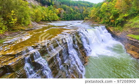 Up close with drone to beautiful waterfall eroding cliffs with colorful forests around Up close with drone to beautiful waterfall eroding cliffs with colorful forests around 97208900