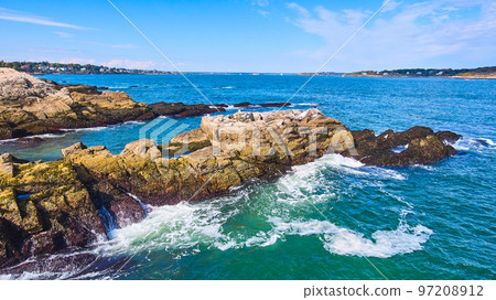 Waves crashing against rocks on coast in Maine with houses in background Waves crashing against rocks on coast in Maine with houses in background 97208912