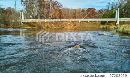 At water level over river with view of suspension bridge in late fall At water level over river with view of suspension bridge in late fall 97208939