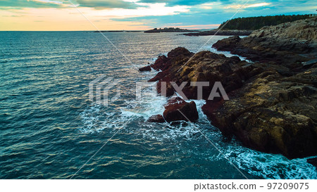 Serene ocean view over coasts of Maine with rocky coasts, waves crashing, and sunset light Serene ocean view over coasts of Maine with rocky coasts, waves crashing, and sunset light 97209075