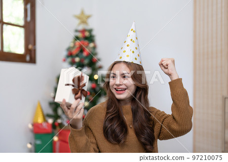 Portrait of smiling asian woman with Christmas gift at home Portrait of smiling asian woman with Christmas gift at home 97210075