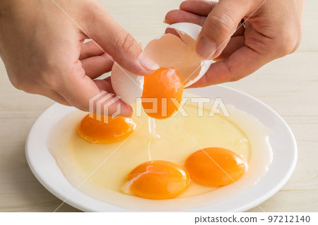 Hand breaking a raw egg egg Hand breaking a raw egg egg 97212140