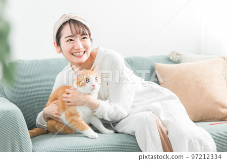 Asian woman owner holding a cat on the sofa at home 97212334