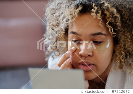 Close-up of young woman putting hydrating under eye patches 97212672