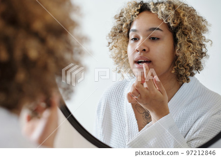African American woman applying nourishing balm on lips 97212846