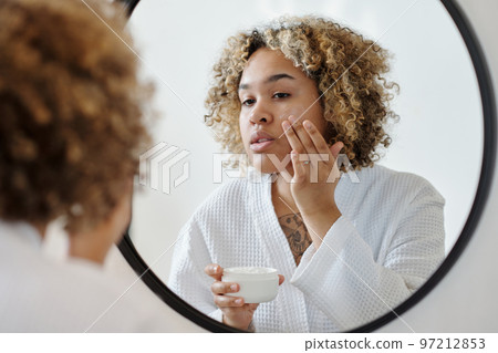 Young attractive woman applying moisturizing cream on face Young attractive woman applying moisturizing cream on face 97212853