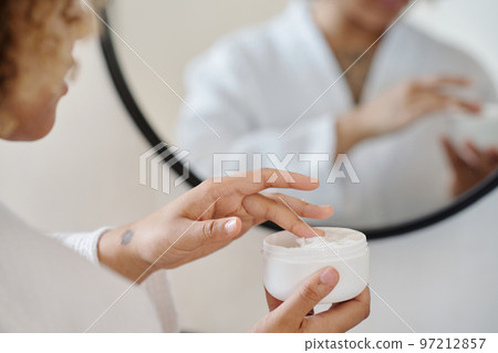 Focus on hand of young woman taking moisturizing cream Focus on hand of young woman taking moisturizing cream 97212857
