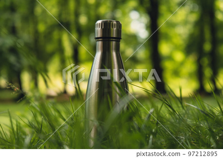 Water bottle. Reusable steel thermo water bottle on green grass. Sustainable lifestyle. Plastic free zero waste free living. Go green Environment protection 97212895