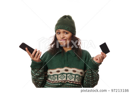 Frustrated brunette woman in warm wool clothes, holding her mobile phone, expresses disappointment due to a failed transaction or rejected payment, lack of cash on her credit card, on white background Frustrated brunette woman in warm wool clothes, holding her mobile phone, expresses disappointment due to a failed transaction or rejected payment, lack of cash on her credit card, on white background 97213186