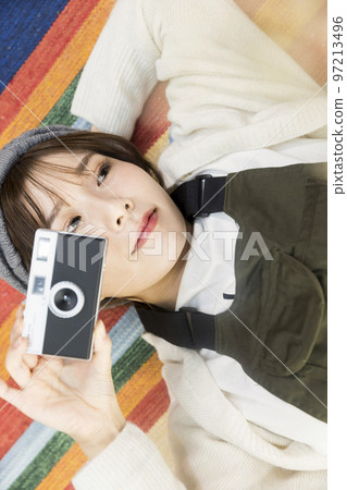 年輕女子躺在地毯上，拿著膠卷相機 97213496