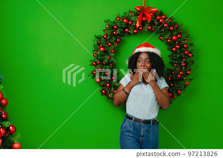 African woman smiling standing against Christmas wreath decor at home 97213826